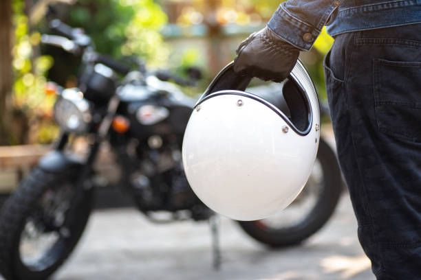 A person is holding a helmet in front of a motorcycle.