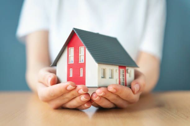 A person is holding a small model house in their hands.