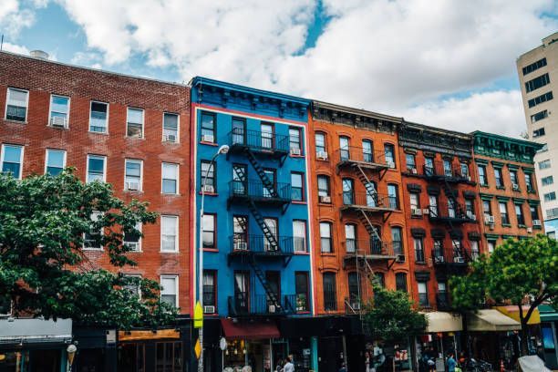 A row of colorful buildings with fire escapes on a city street.