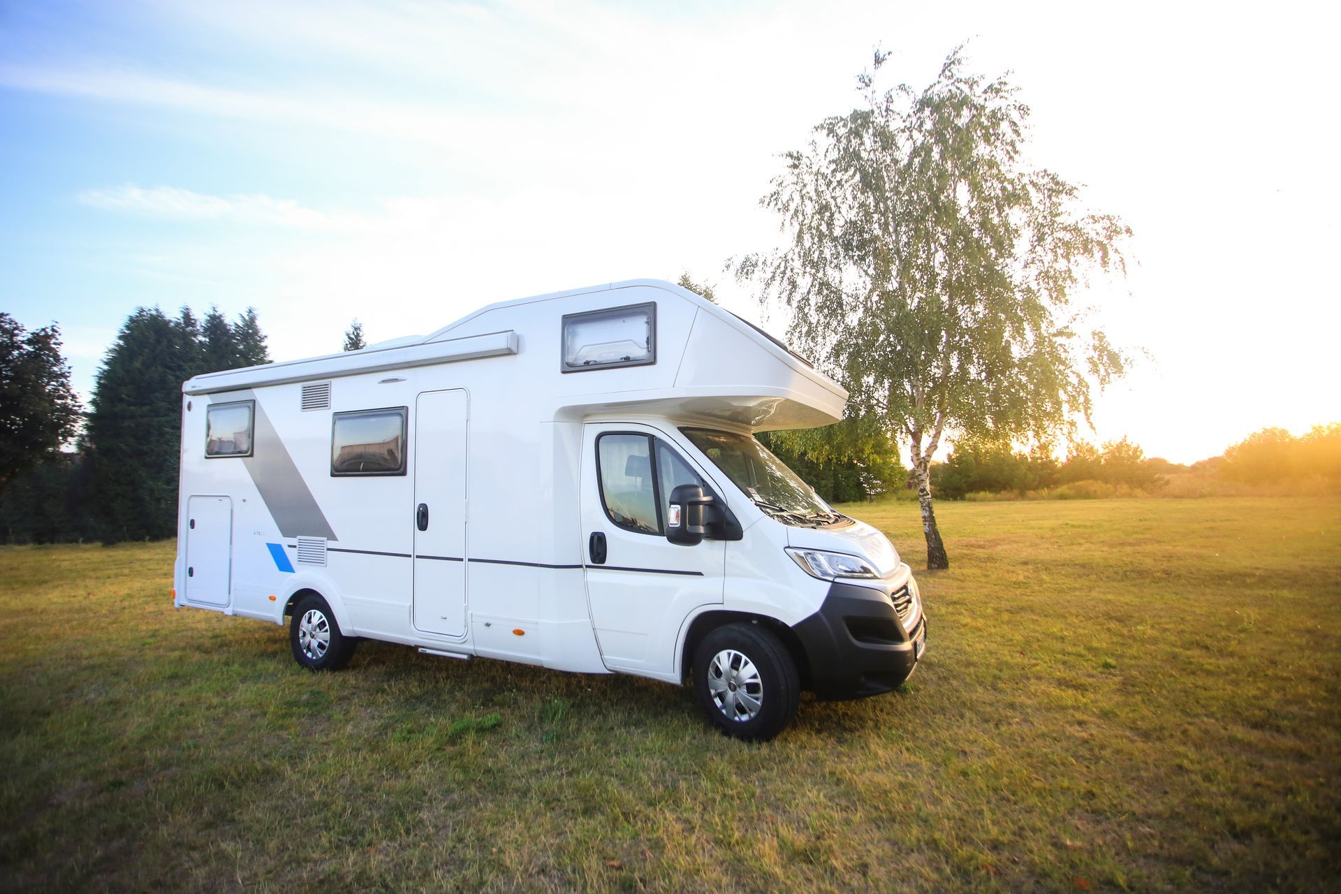 A white rv is parked in a grassy field.