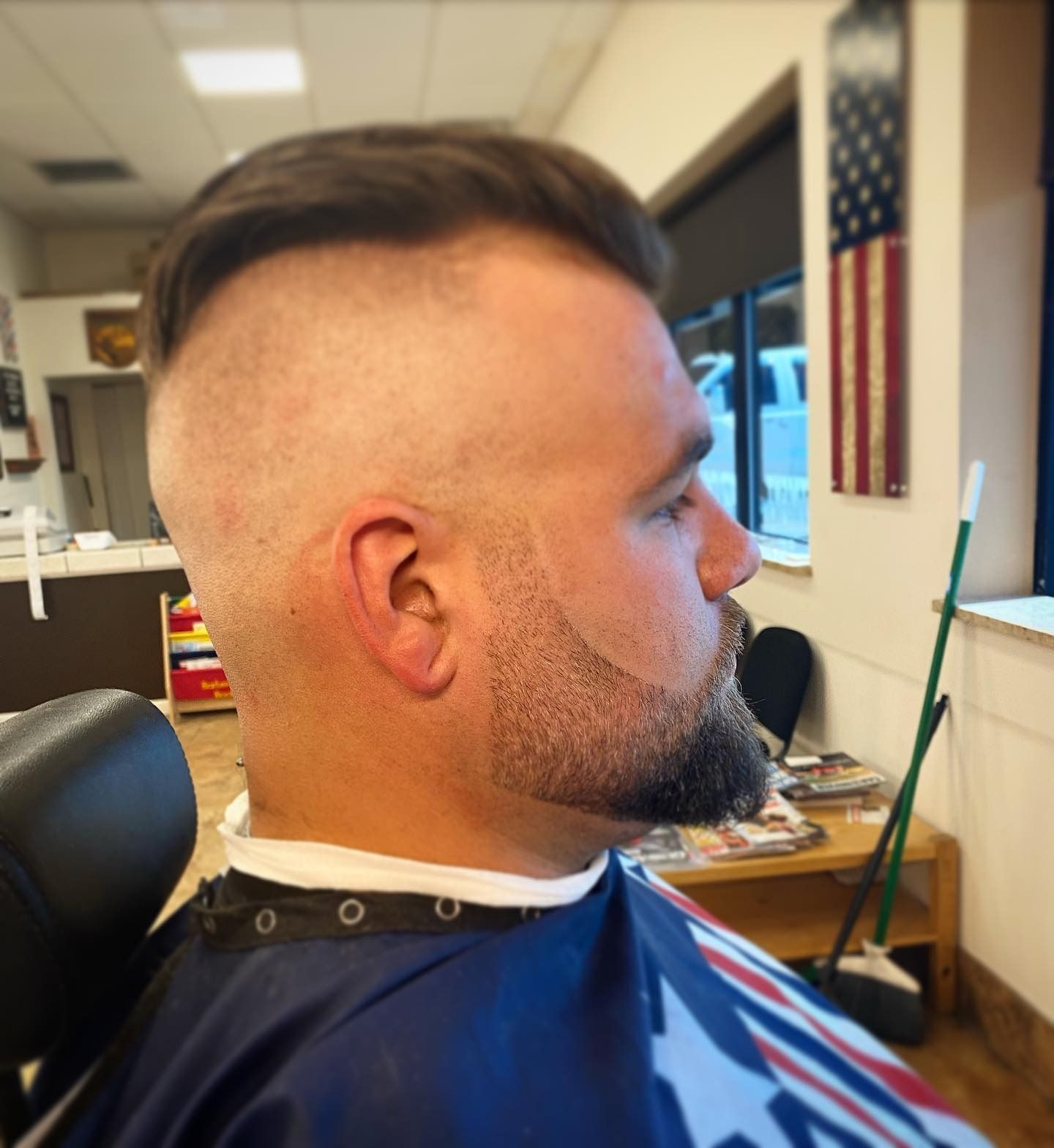 A man with a beard is getting his hair cut at a barber shop