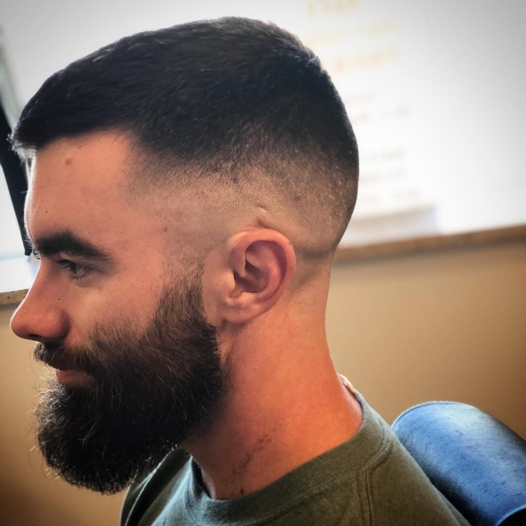 A man with a beard and short hair is sitting in a chair.