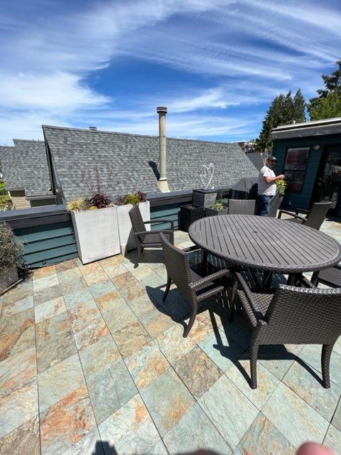 Patio with outdoor furniture and a person standing by a door, blue sky, and tiled floor.