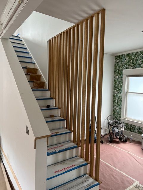 Staircase with wooden slat partition. Steps covered in blue protective film.