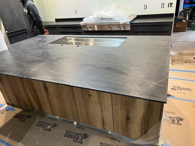 Kitchen island with dark countertop and wood-grain cabinet. A range is in the background.