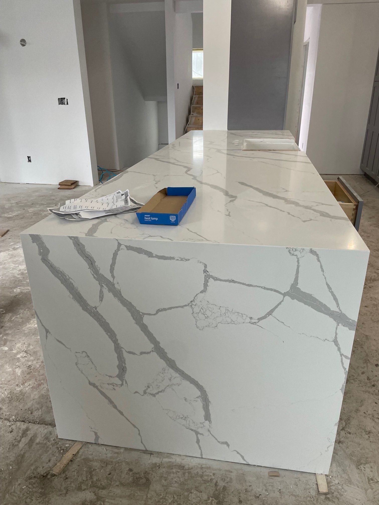 White kitchen island with gray veining in a construction setting.