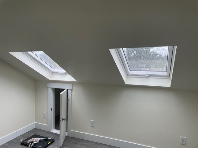 Interior of a room with two skylights and a doorway with an open door. Beige walls.