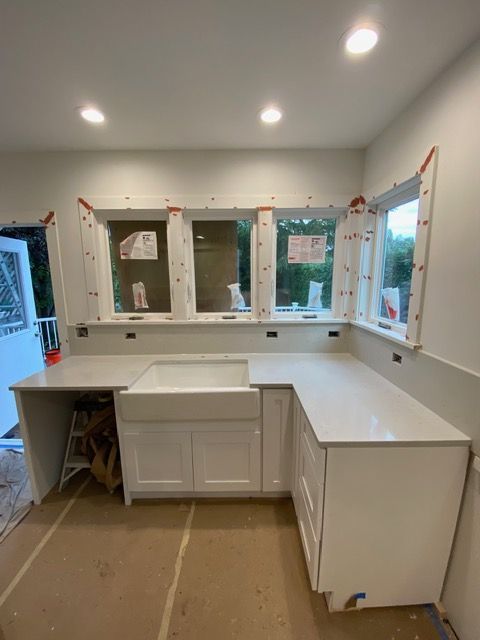White kitchen renovation with countertops, sink, cabinets, and windows.