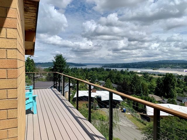 Deck overlooking a scenic landscape with trees, water, and cloudy sky.