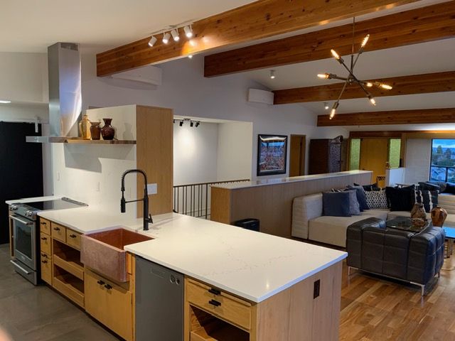 Modern kitchen with island, wooden cabinets, stainless steel appliances, and open living area.