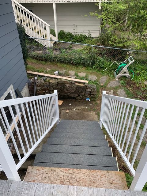 Gray steps with white railing leading to a backyard.
