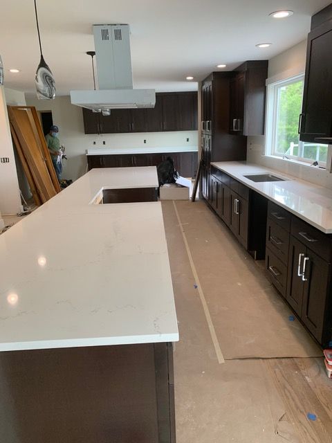Newly remodeled kitchen with dark brown cabinets, white countertops, and a stainless steel range hood.