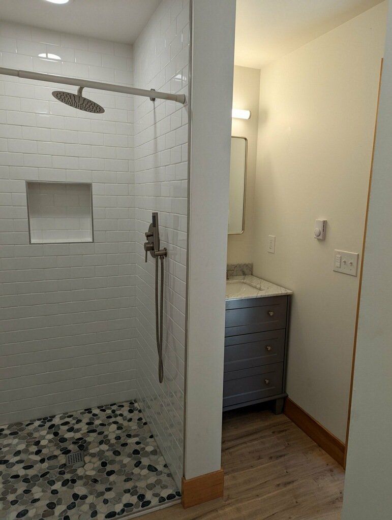 Bathroom with a tiled shower stall and vanity. Gray and white color scheme.