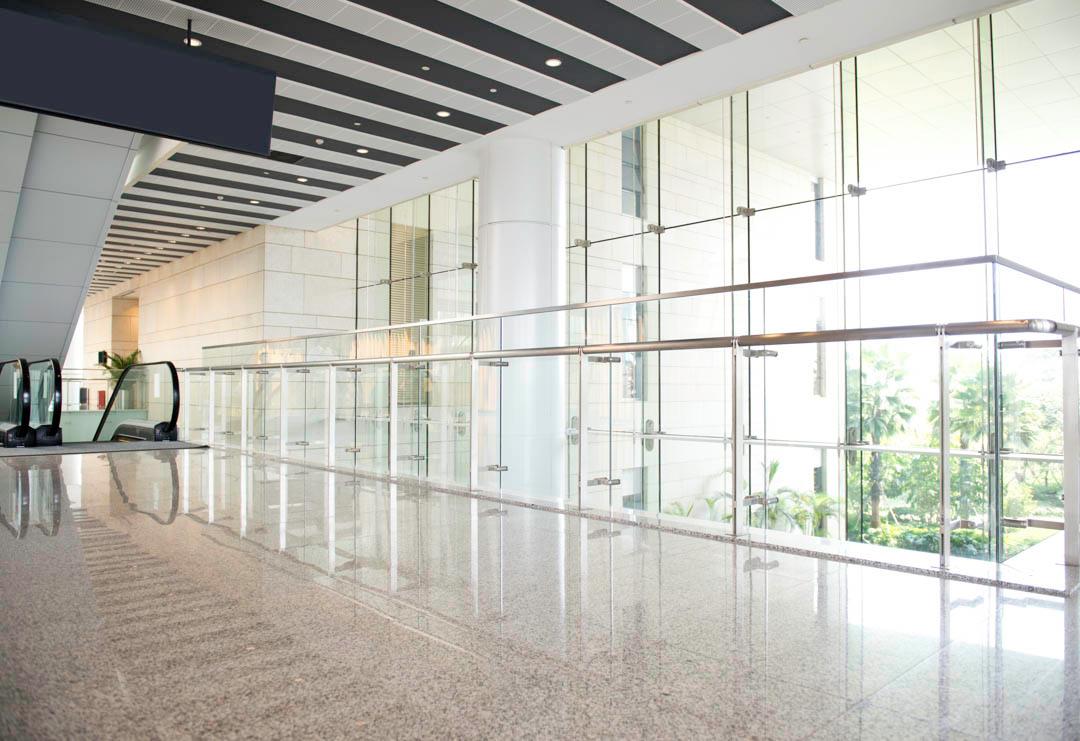 An empty hallway in a building with a lot of windows and an escalator.