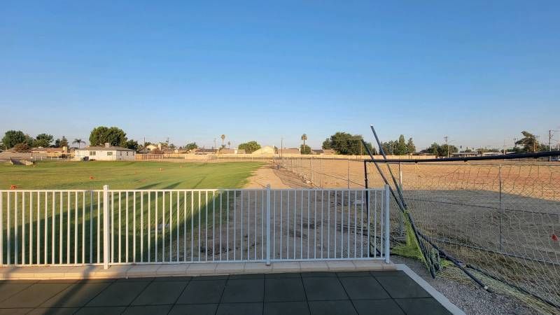 A white fence surrounds a lush green field.