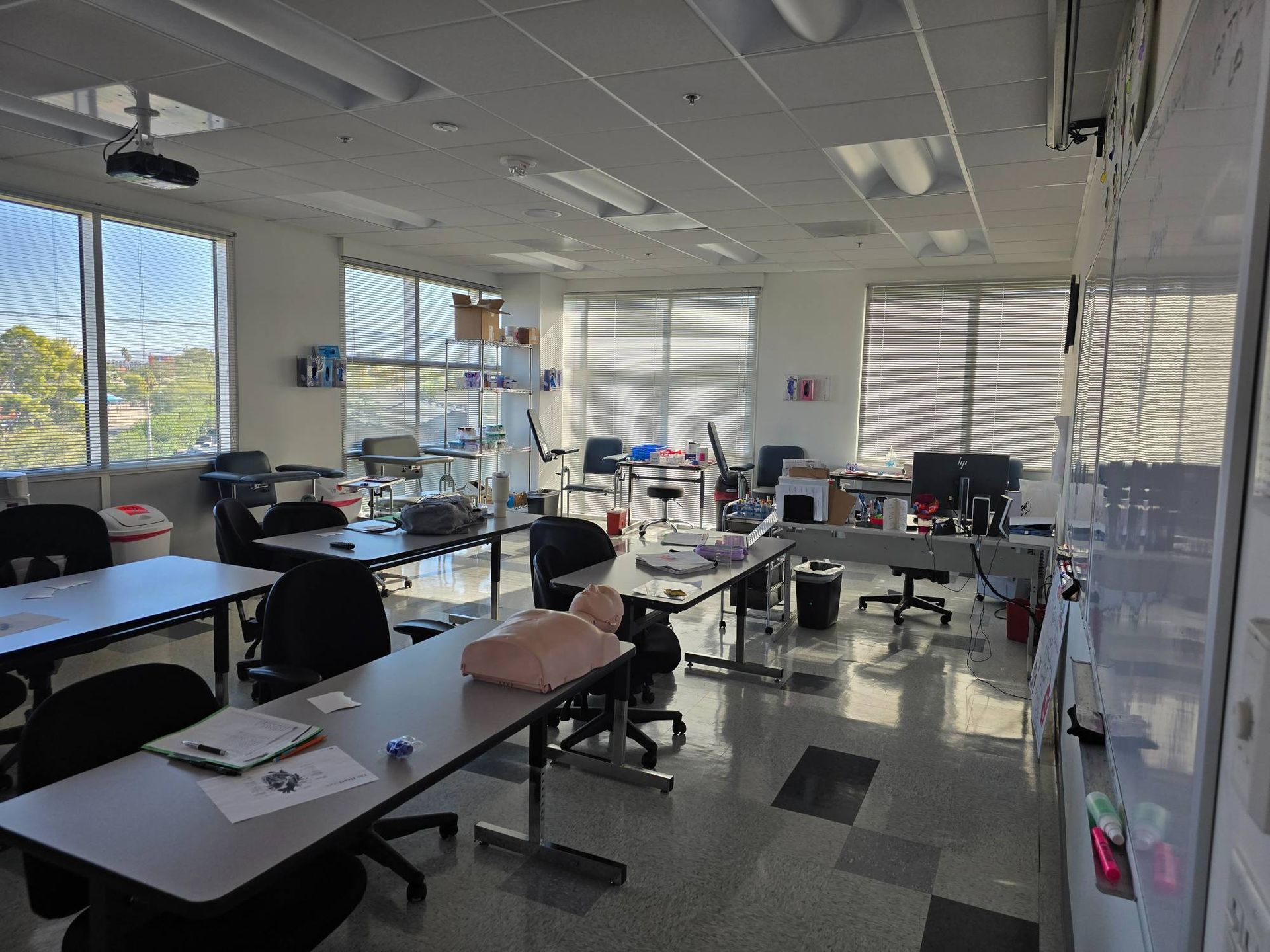 A large room with tables and chairs and a mannequin on the floor.