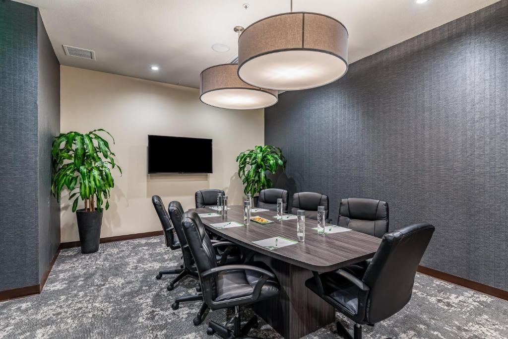 A conference room with a long table and chairs and a flat screen tv.