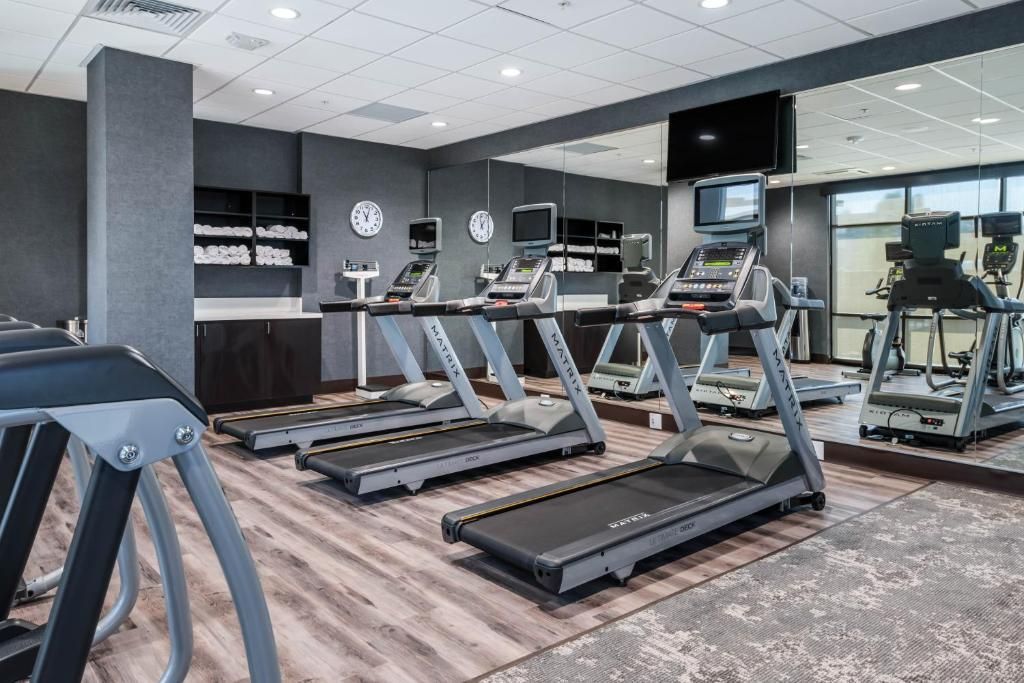 A gym with a lot of treadmills and a large mirror.