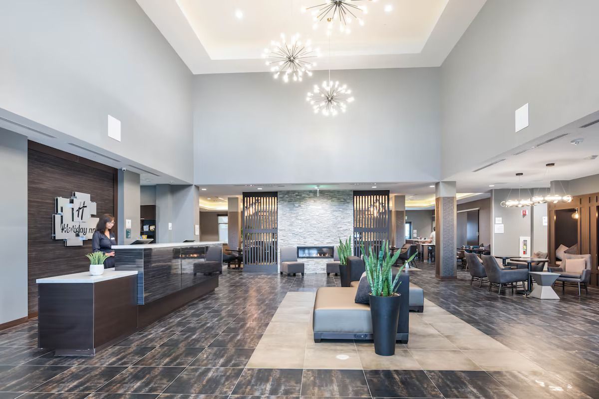 A large lobby of a hotel with a reception desk and a fireplace.