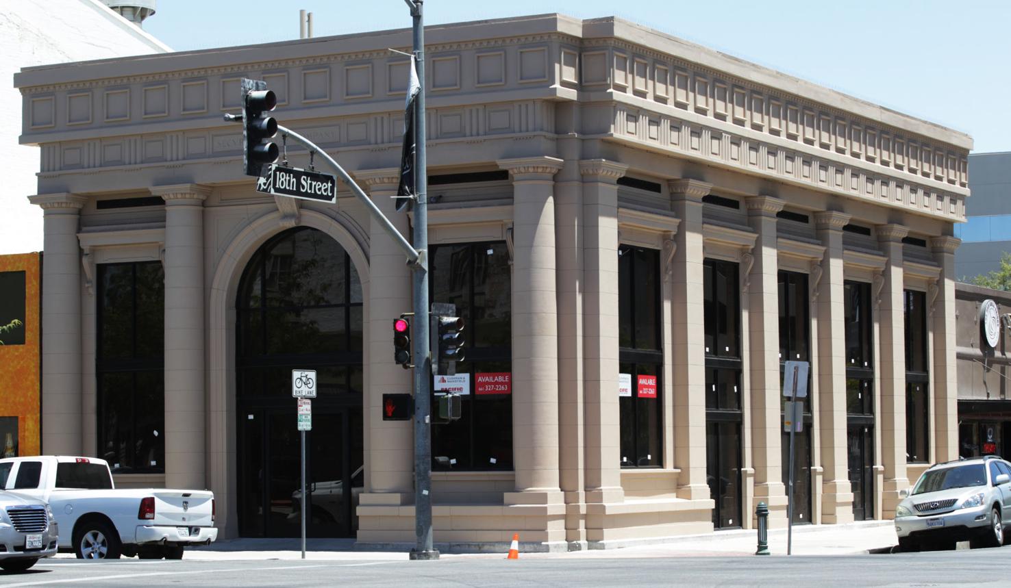 A white truck is parked in front of a large building