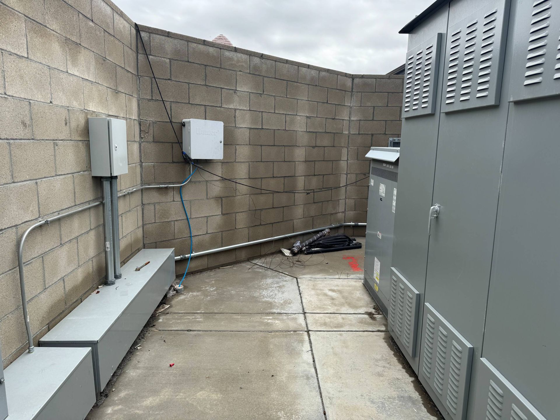 A row of electrical boxes are lined up next to a brick wall.