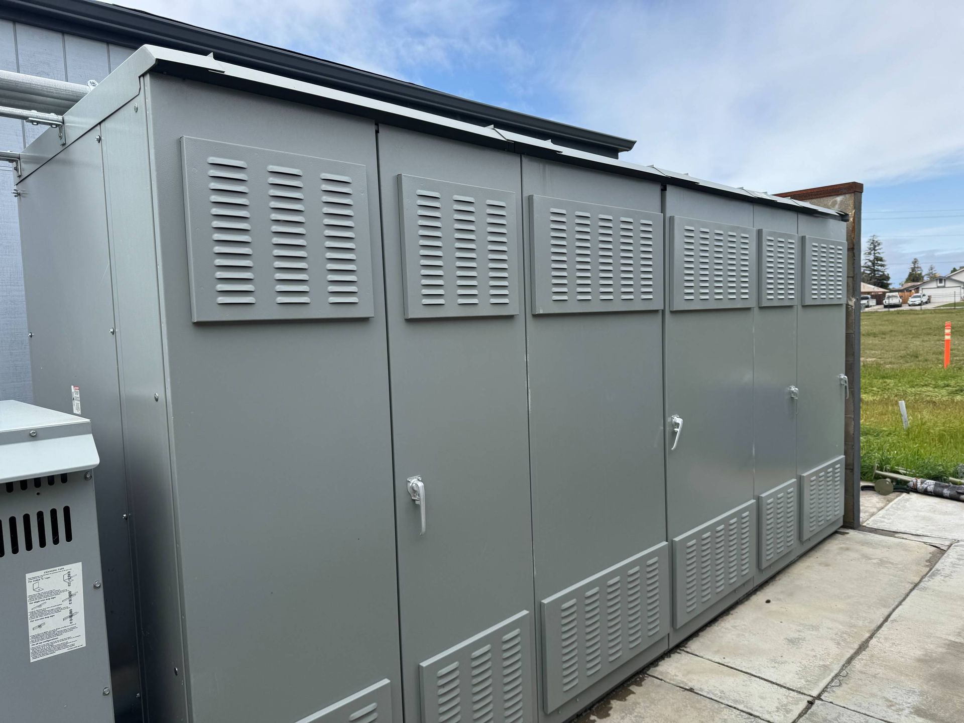 A row of electrical cabinets are sitting outside of a building.