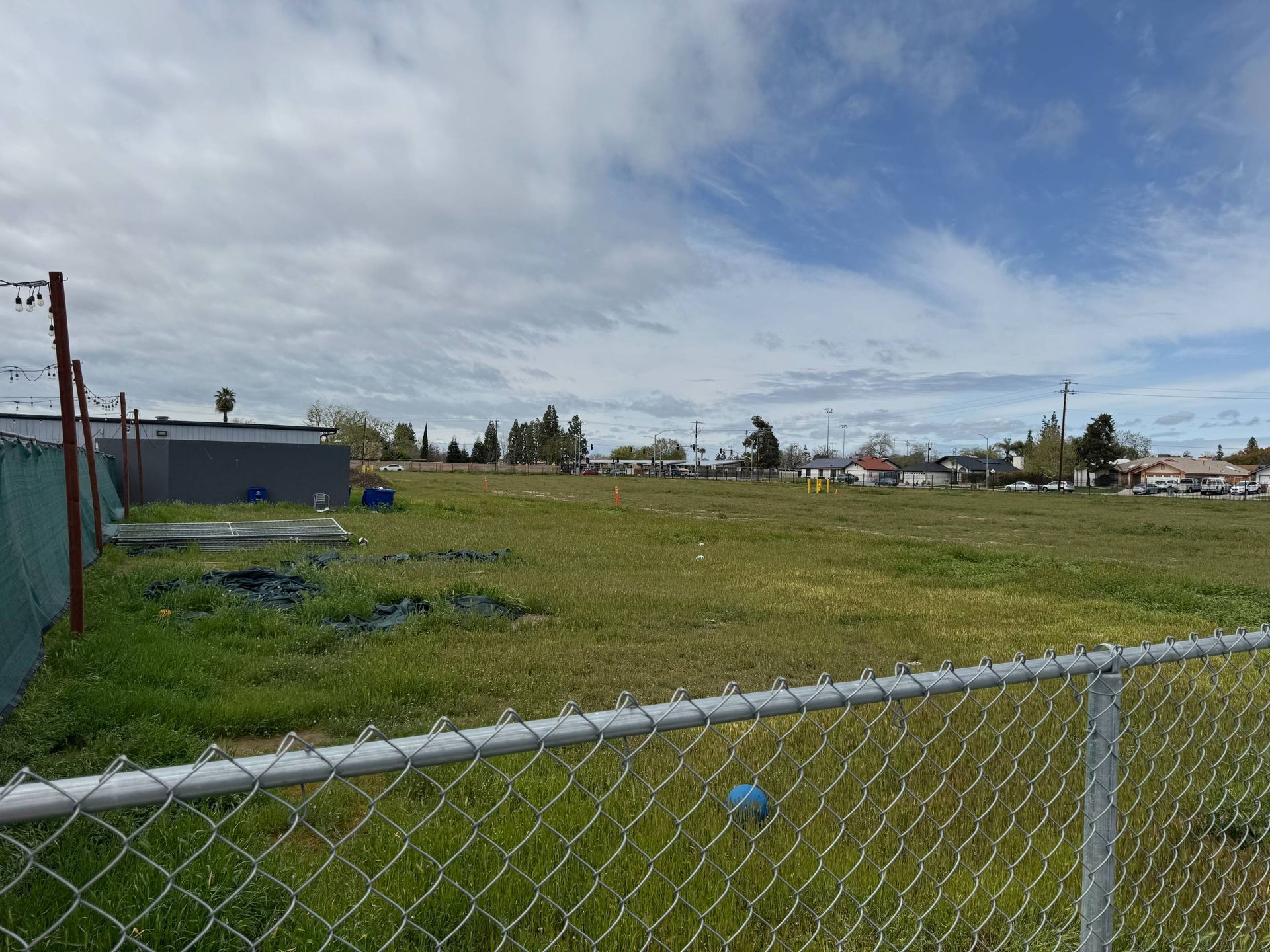 A chain link fence surrounds a large grassy field.