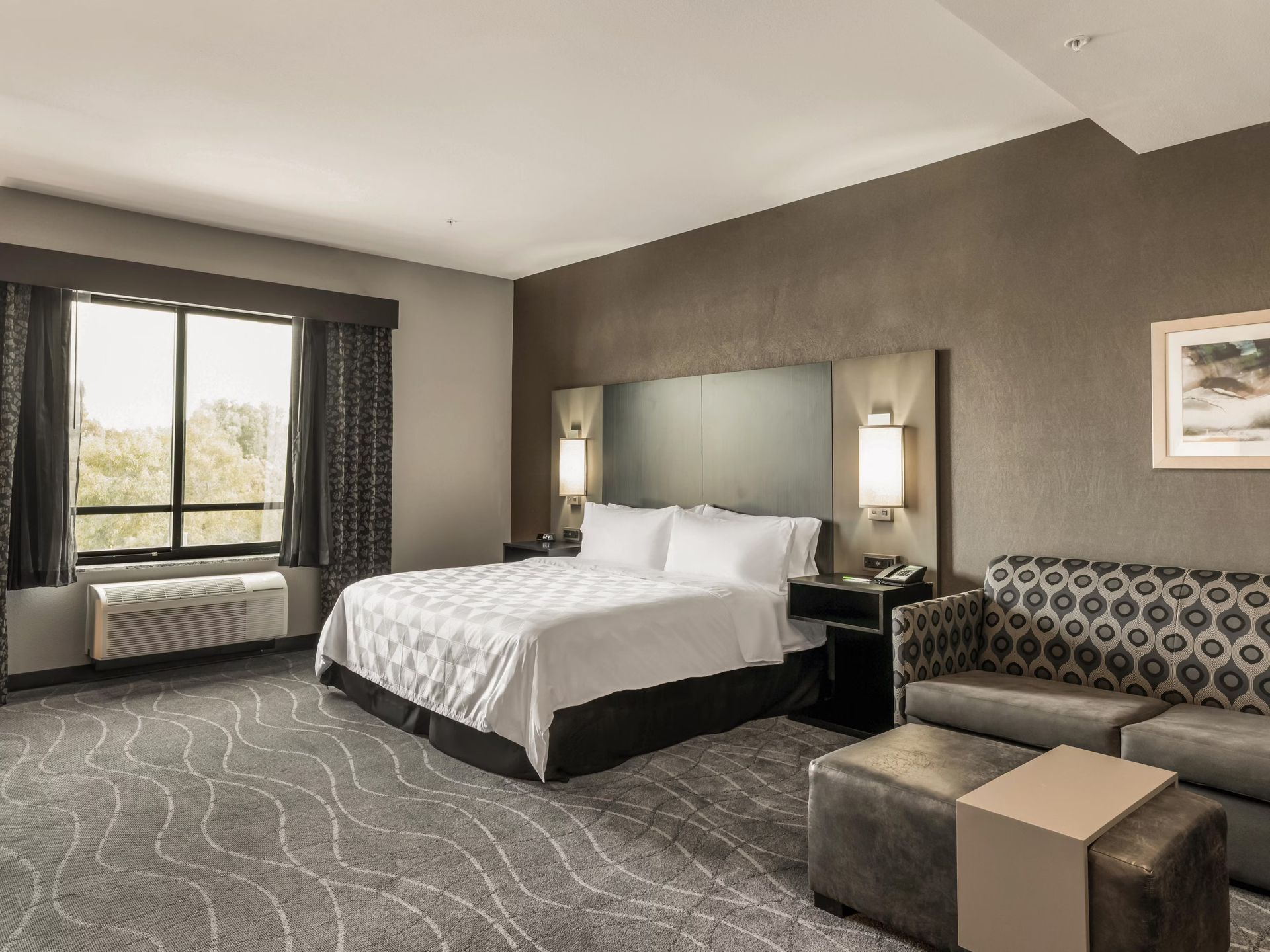 A hotel room with a king size bed and a couch.