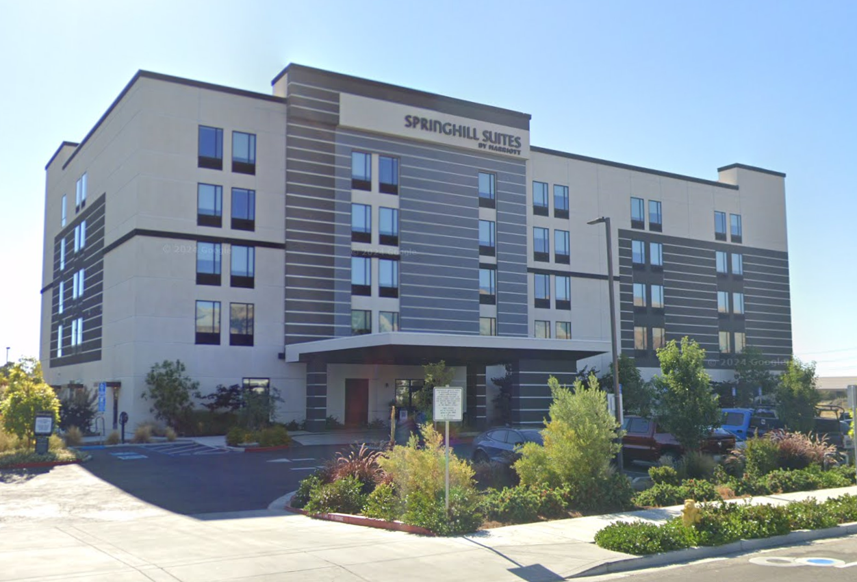 A large building with a lot of windows and a parking lot in front of it