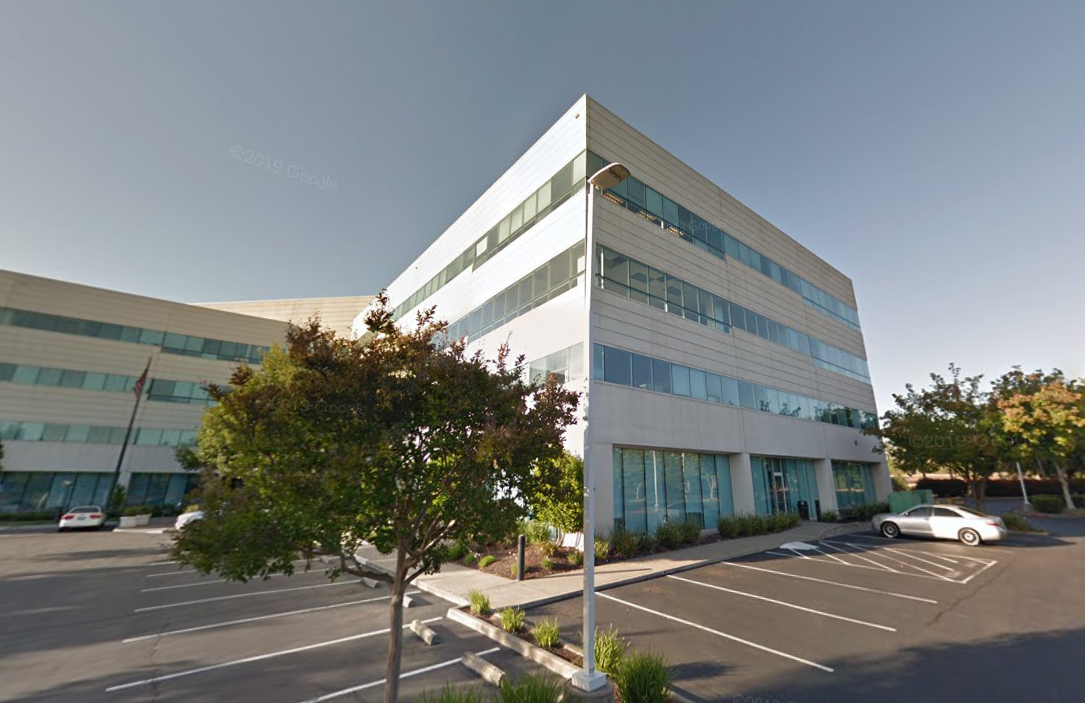 A large white building with a parking lot in front of it.
