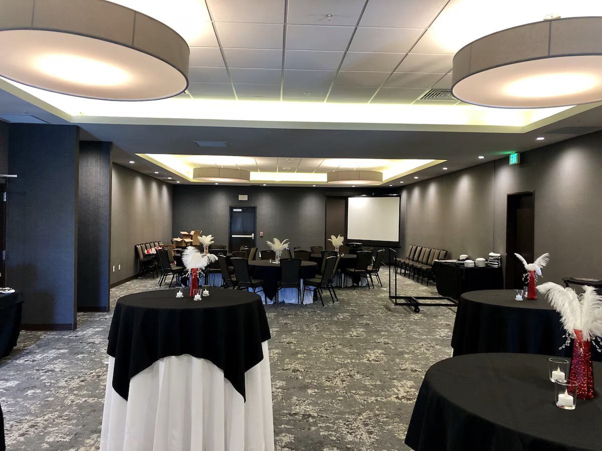 A large room with tables and a projector screen.