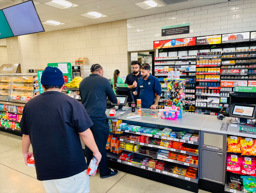 A group of people are standing in a convenience store.