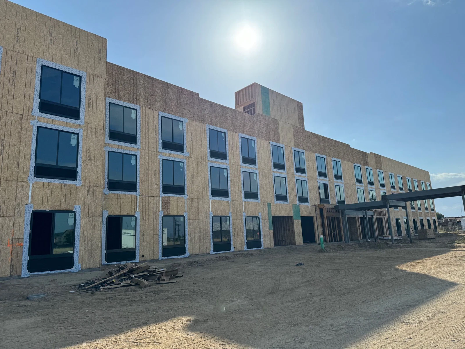 A large building is being built in the middle of a dirt field.