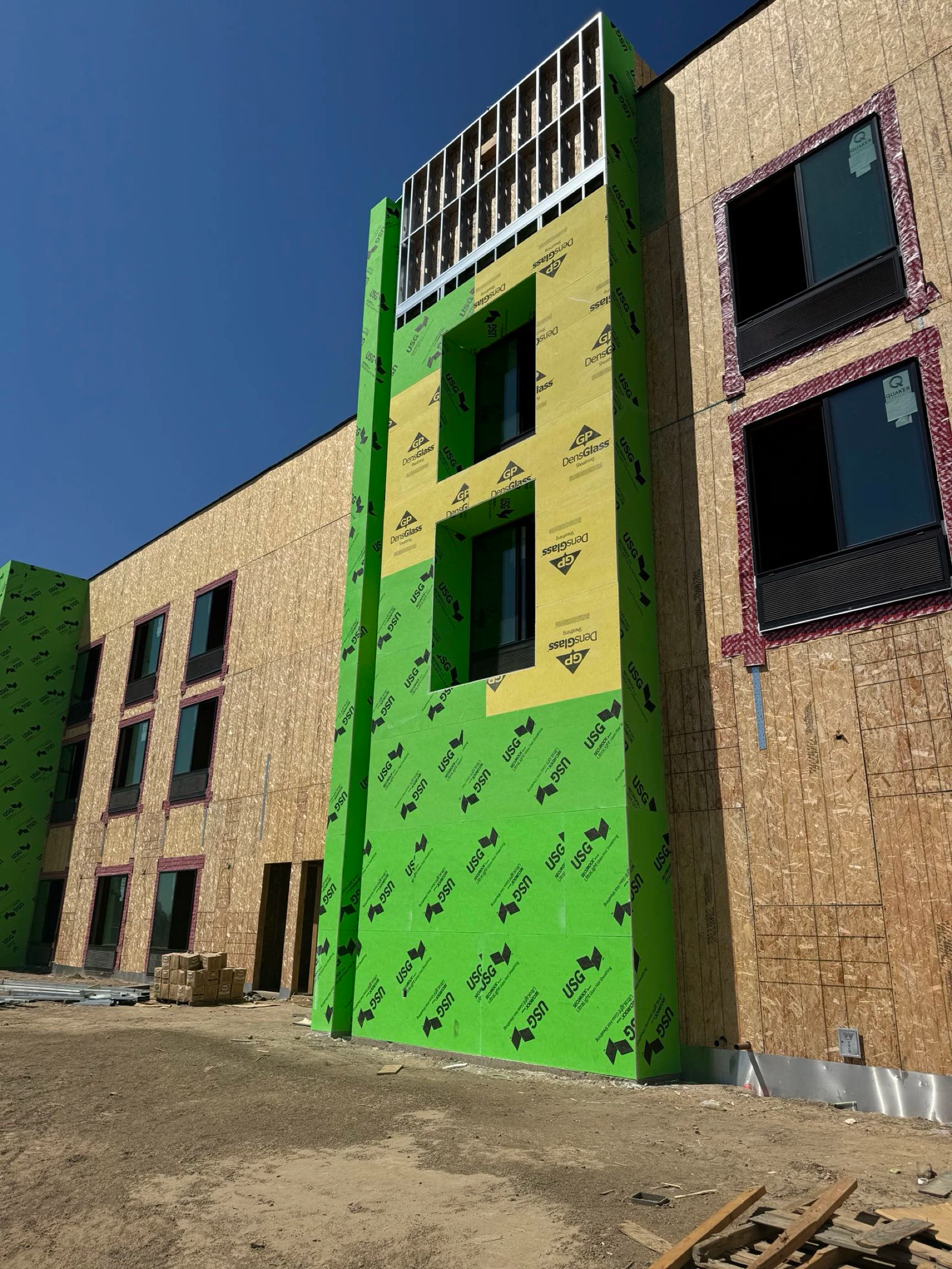 A large building under construction with a green and yellow facade.