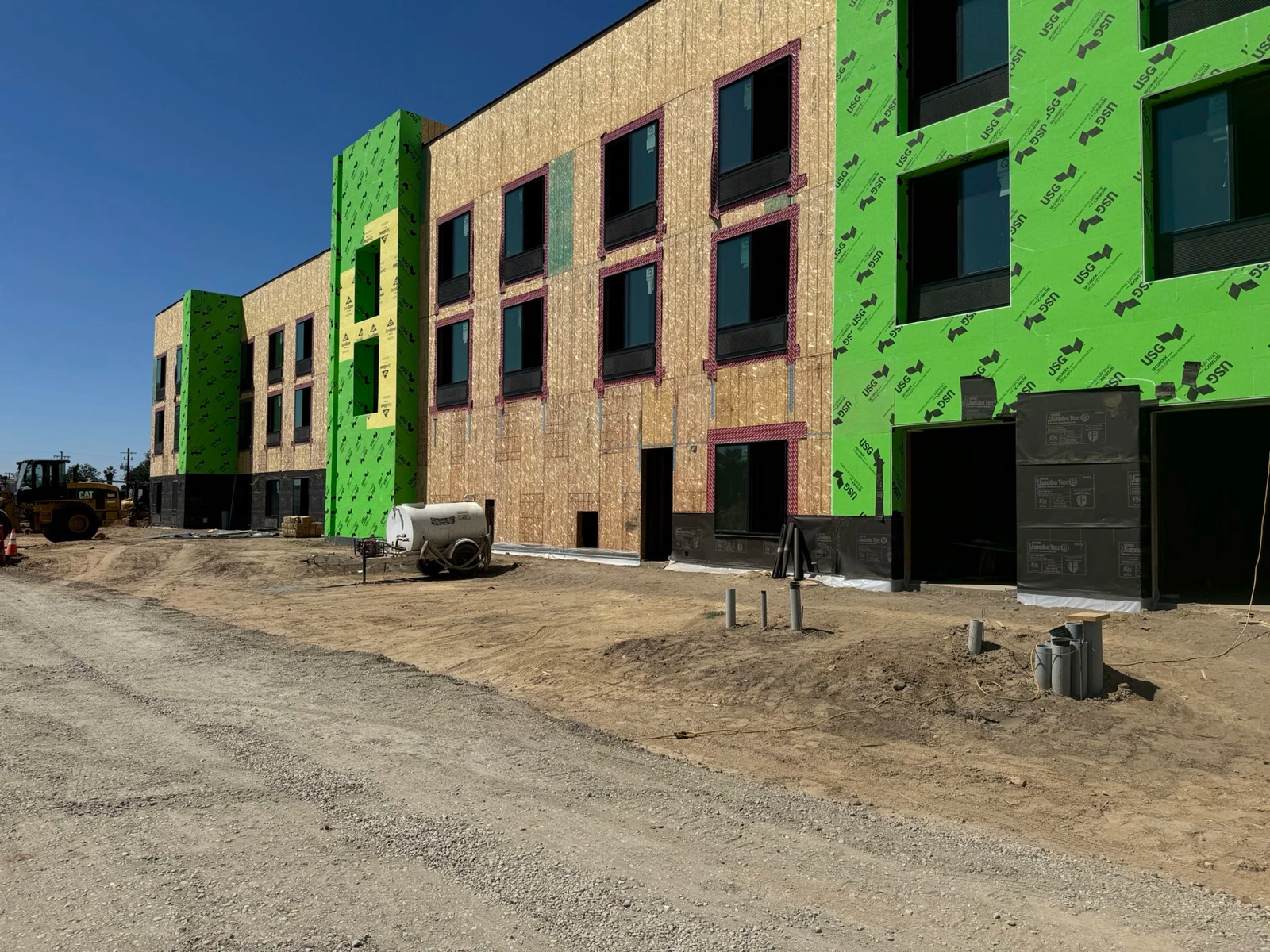 A large building is being built in the middle of a dirt road.