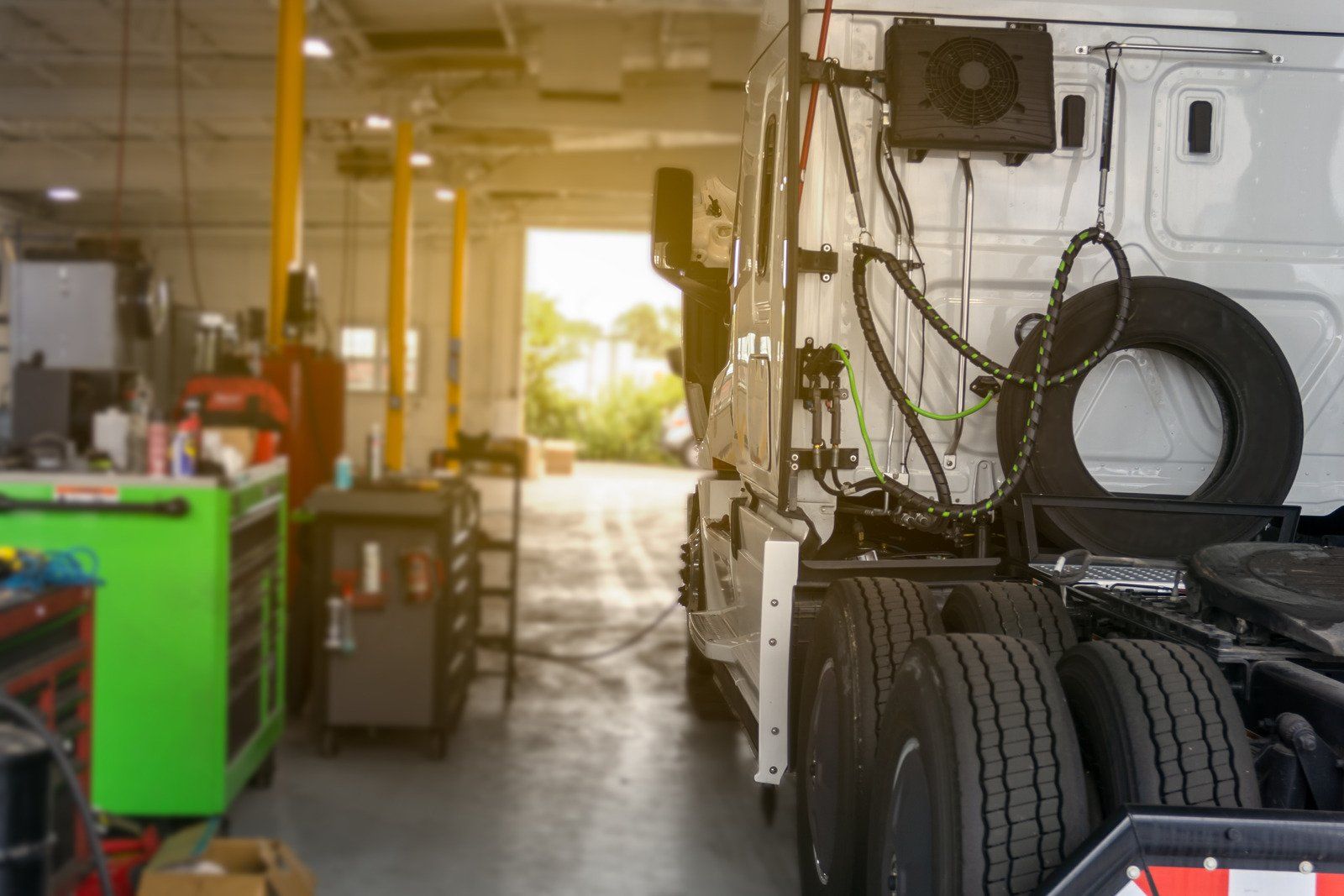 A truck is sitting in a garage with tires on the back of it.