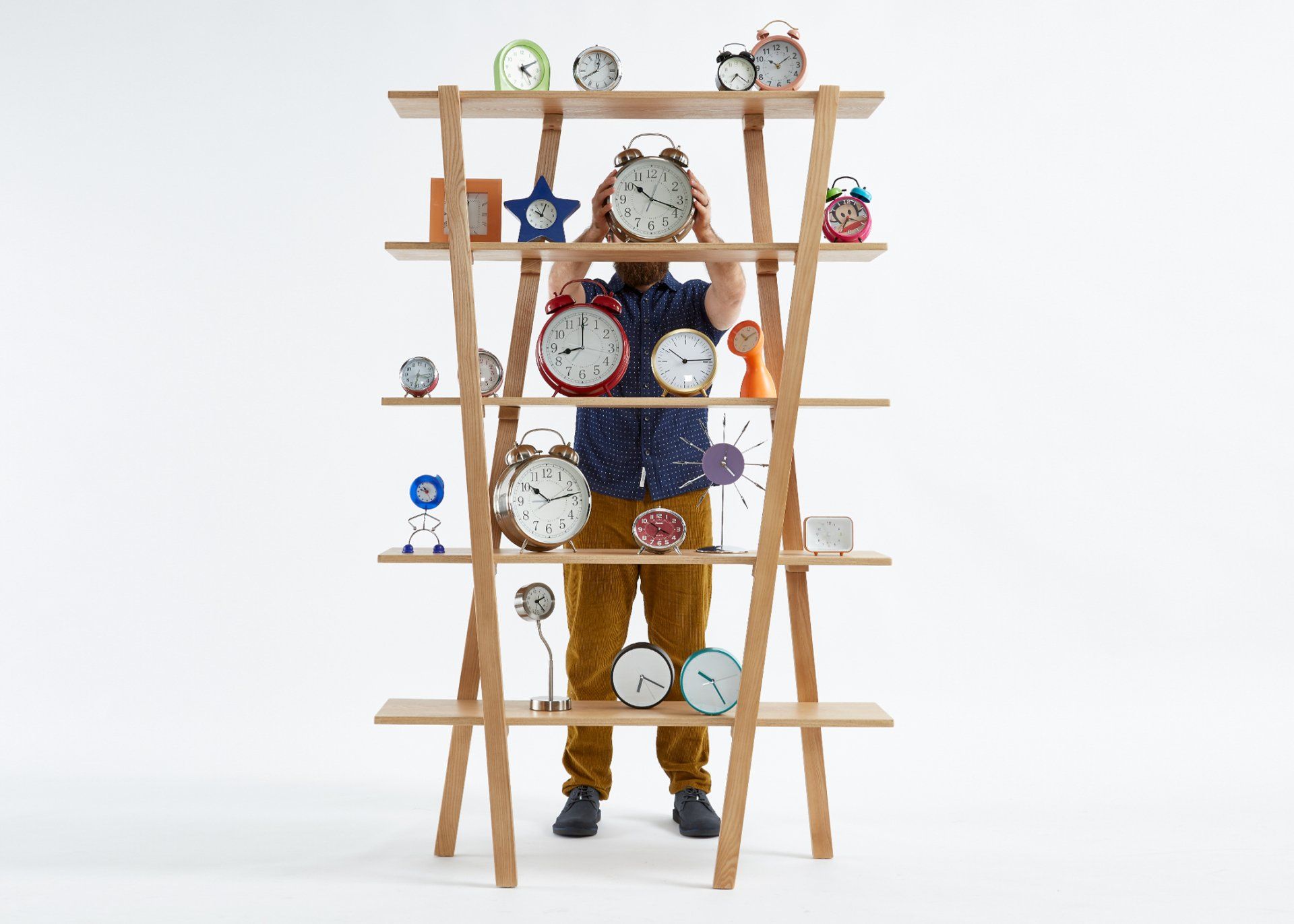 A man is standing in front of a shelf filled with clocks.