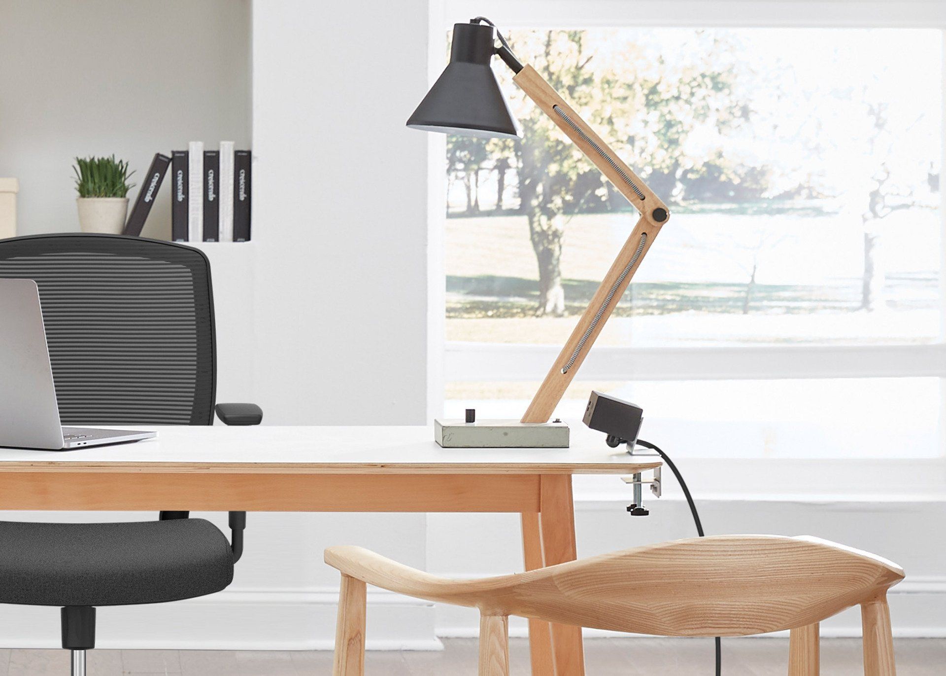 An office with a desk , chair , lamp and laptop.