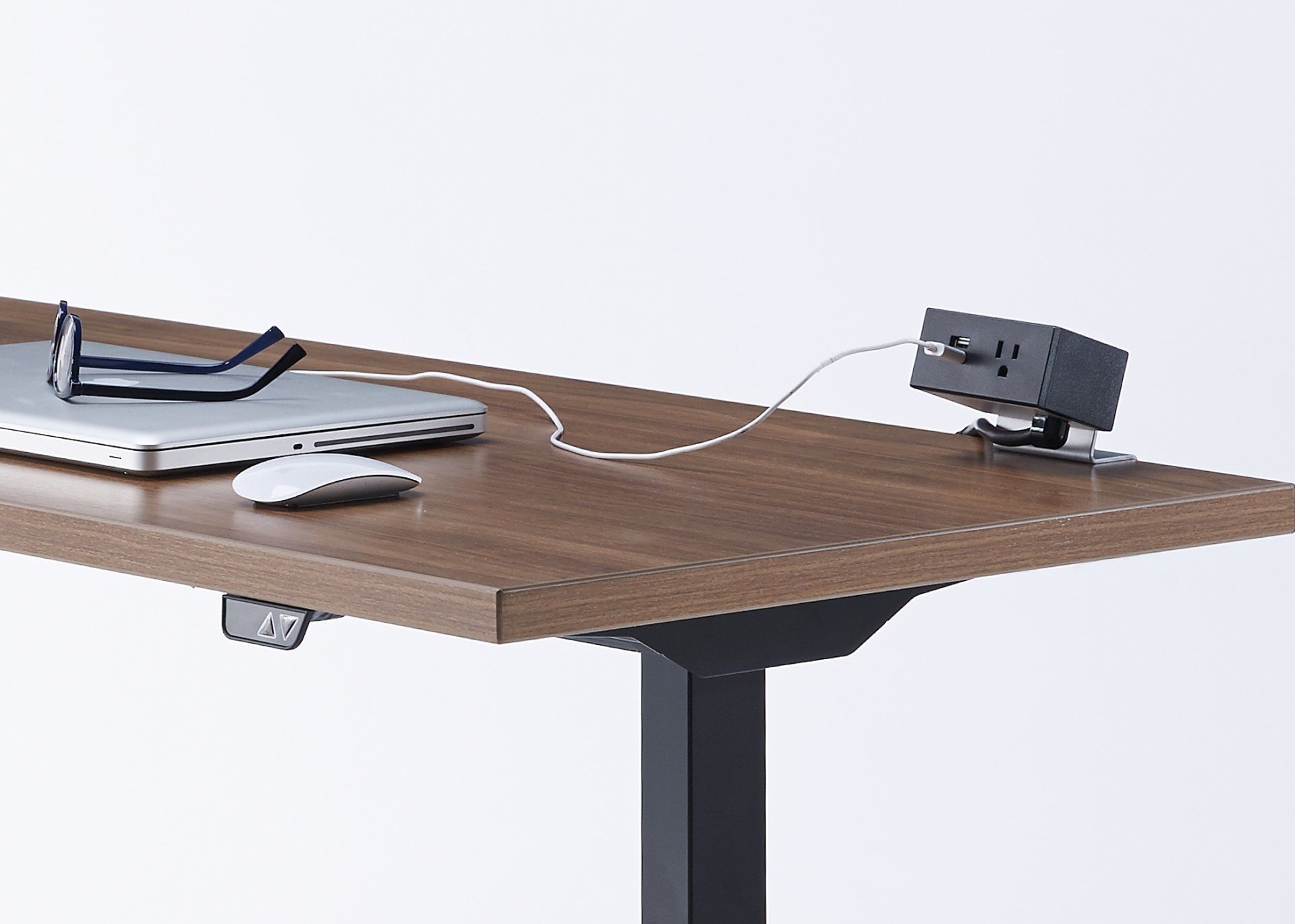 A standing desk with a laptop , mouse , and glasses on it.