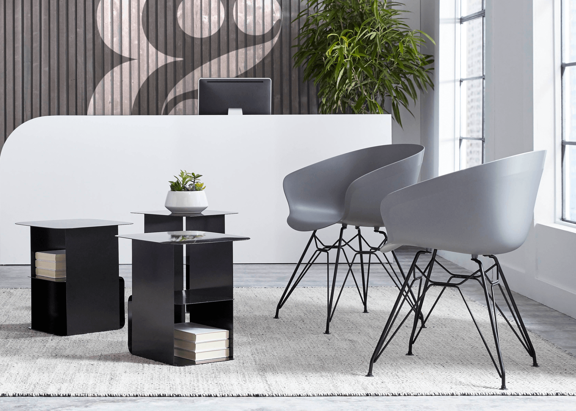 A waiting room with a desk , chairs , tables and a computer.