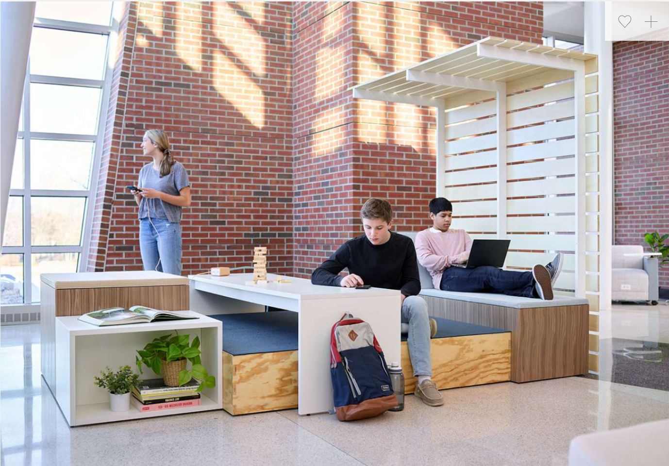 A man is sitting at a table using a laptop while a woman stands behind him.