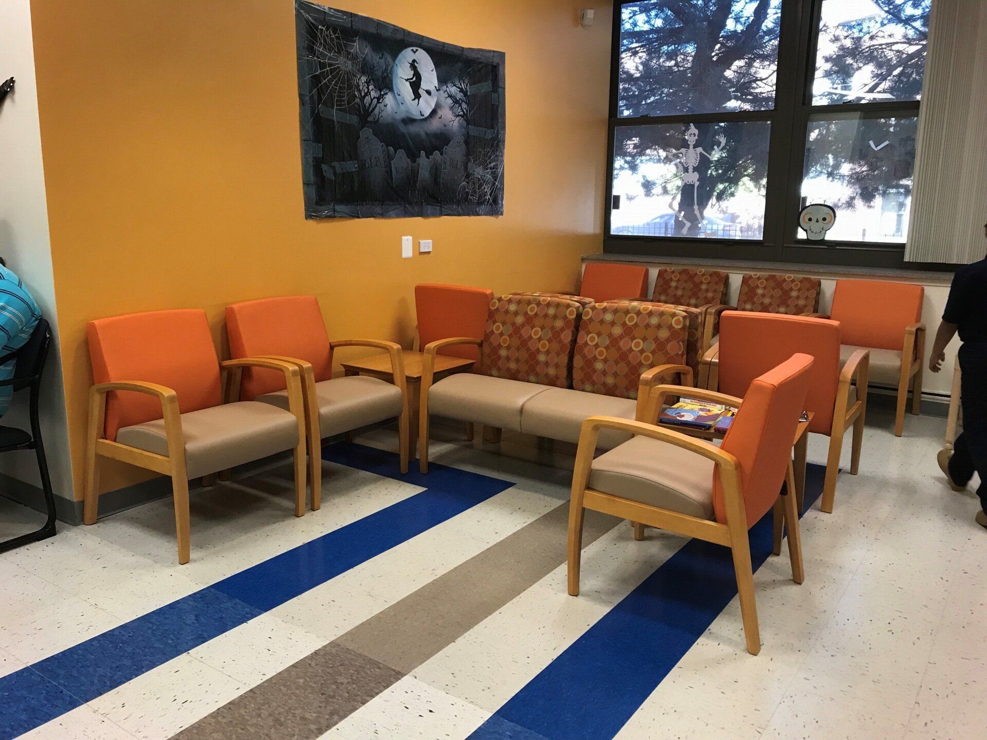 A waiting room with orange chairs and a blue and white striped floor.