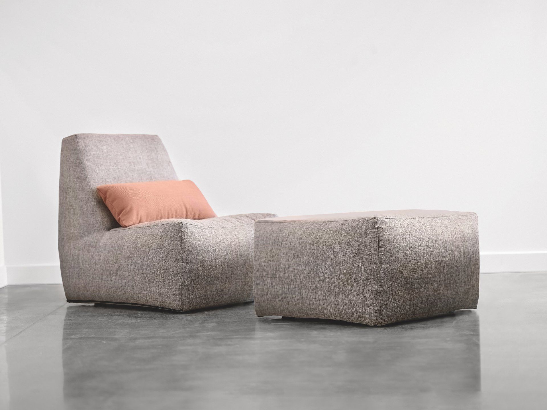 A chair and ottoman are sitting on a concrete floor in a room.