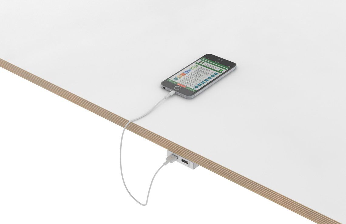 A cell phone is plugged into a charger on a table.