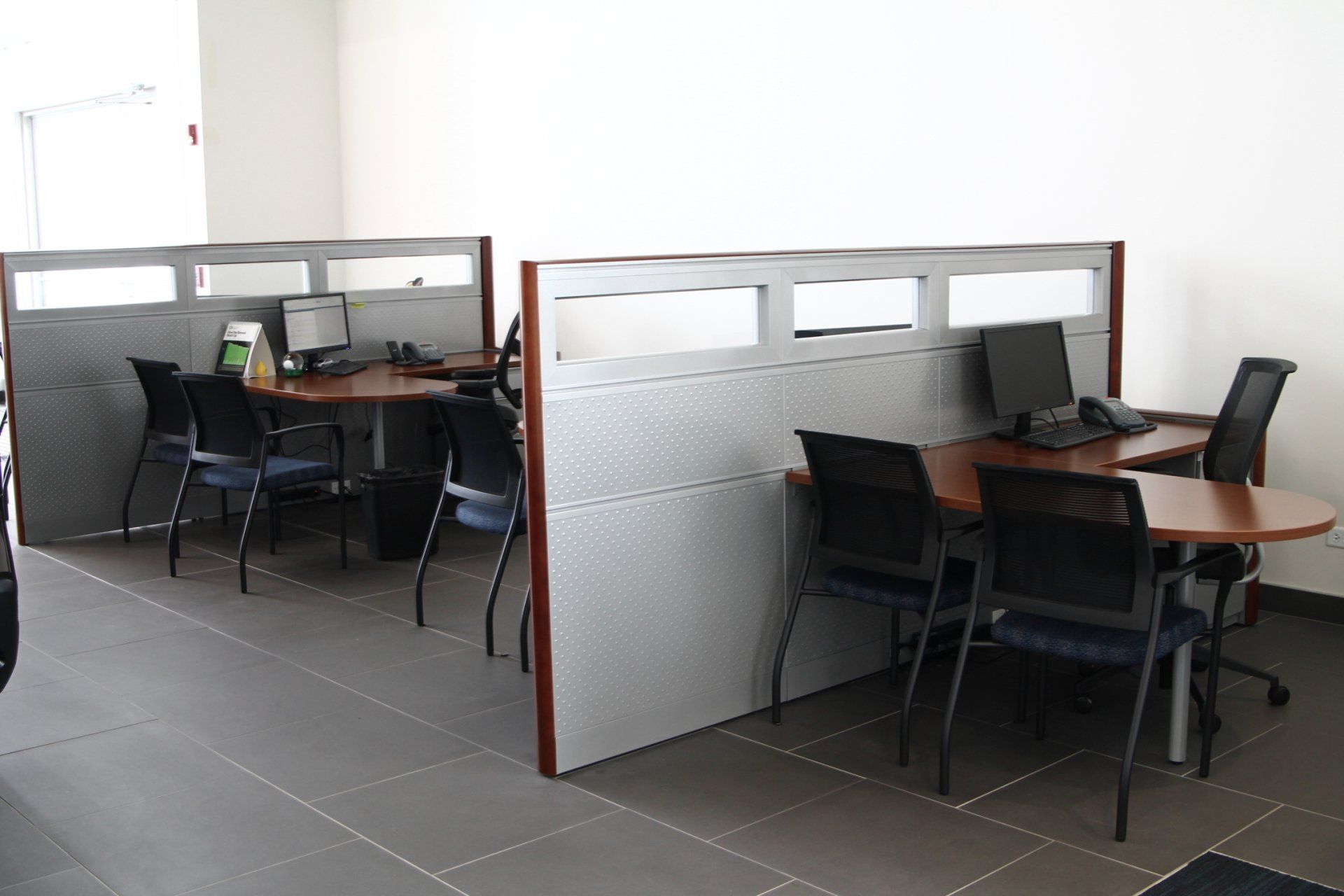 A row of cubicles with tables and chairs in an office