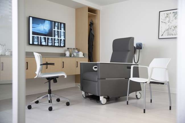 A doctor 's office with a chair , desk and chairs