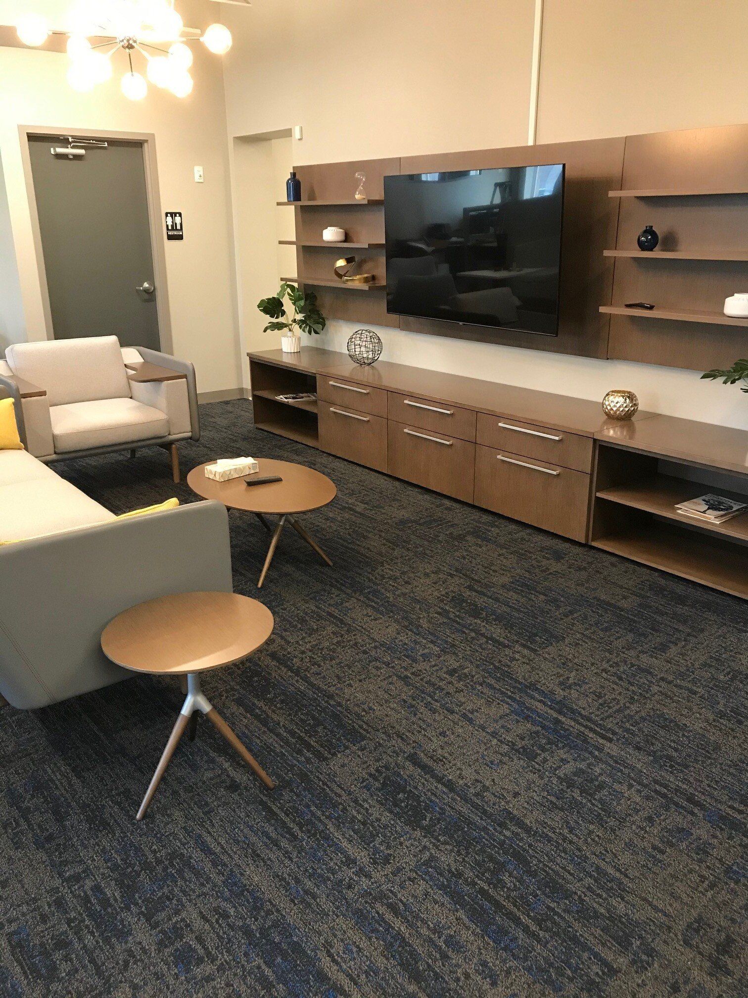 A living room with a couch , chair , tables and a flat screen tv.