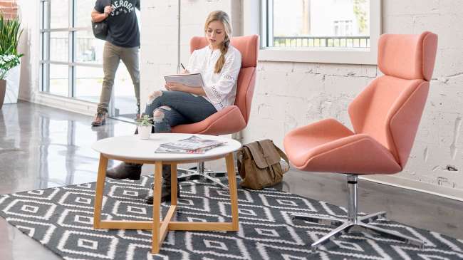 A woman is sitting in a chair next to a table in a room.