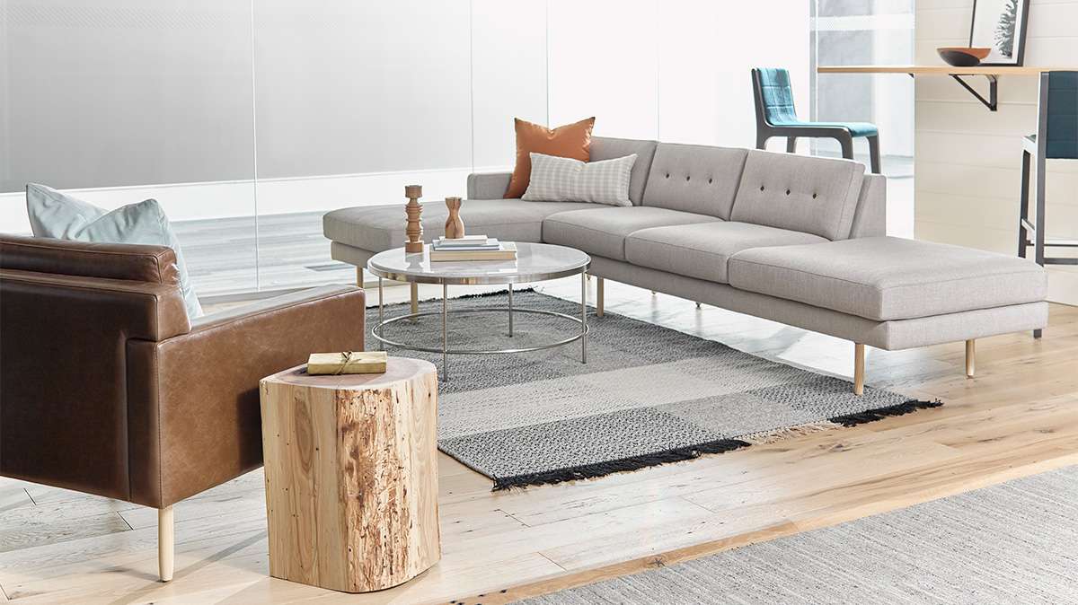 A living room with a sectional couch , chairs , and a coffee table.