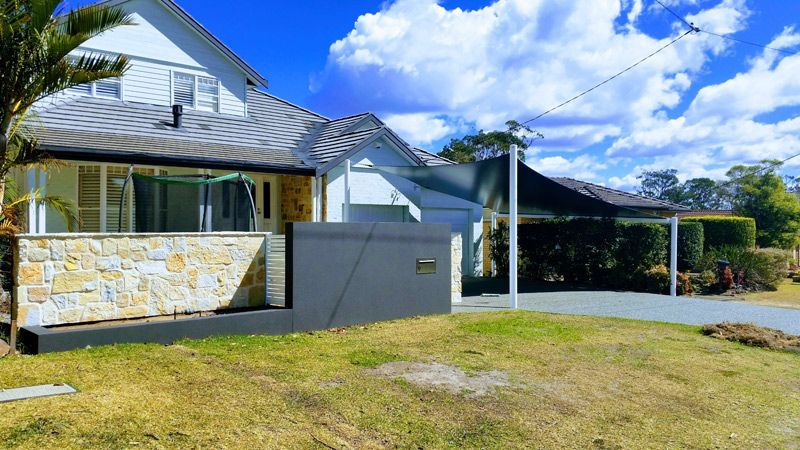 A House With a Stone Wall and Shade Sail — Professional Shade Sail Installations on the Central Coast, NSW